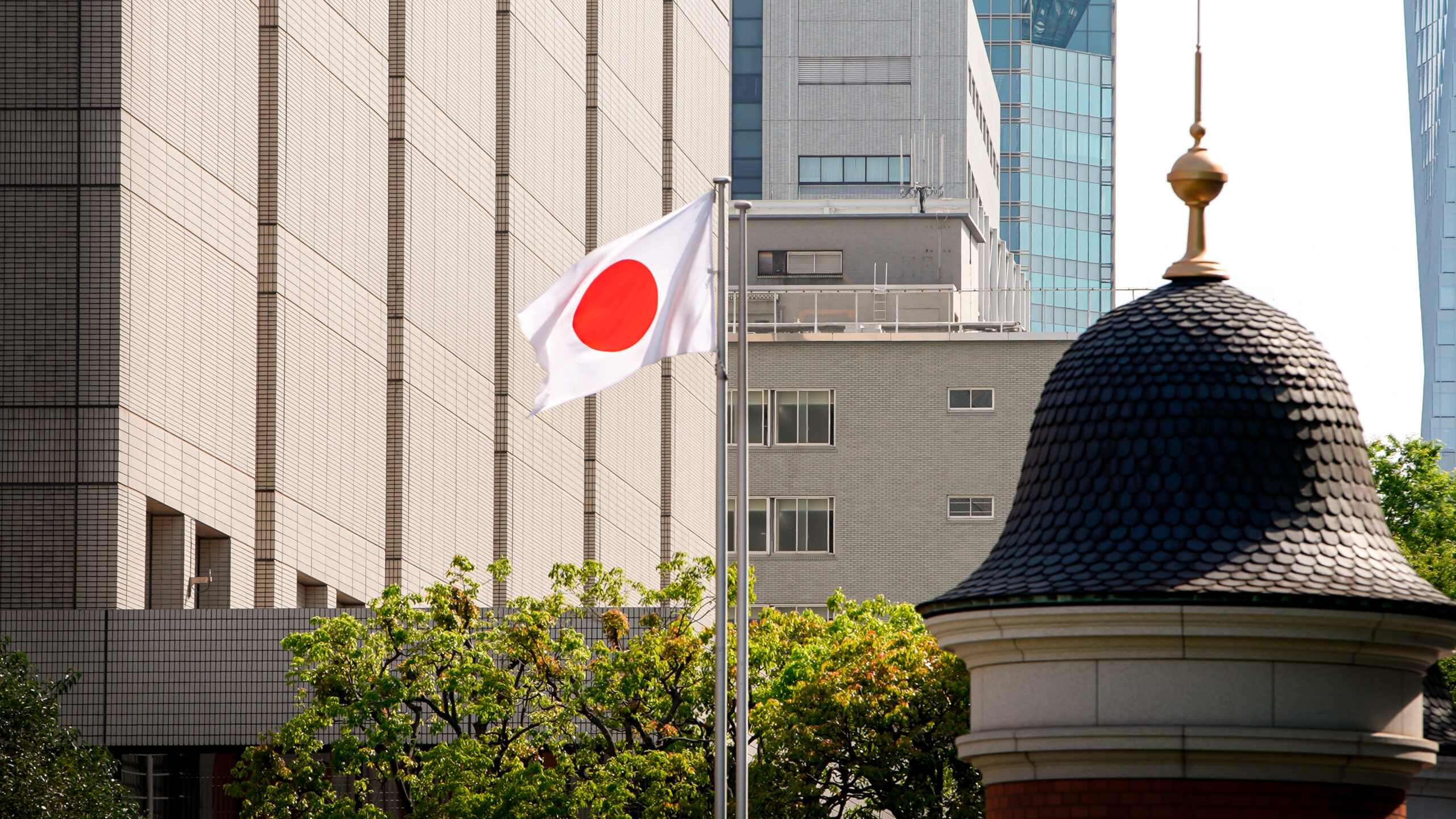 Japanese flag in city. Tower with Japan banner blowing soft silk